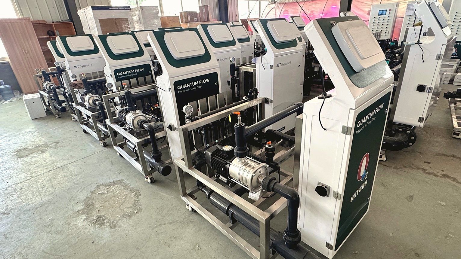 Row of OXYGRO-Inline Quantum Flow fertigation units with green and white cabinets in a workshop